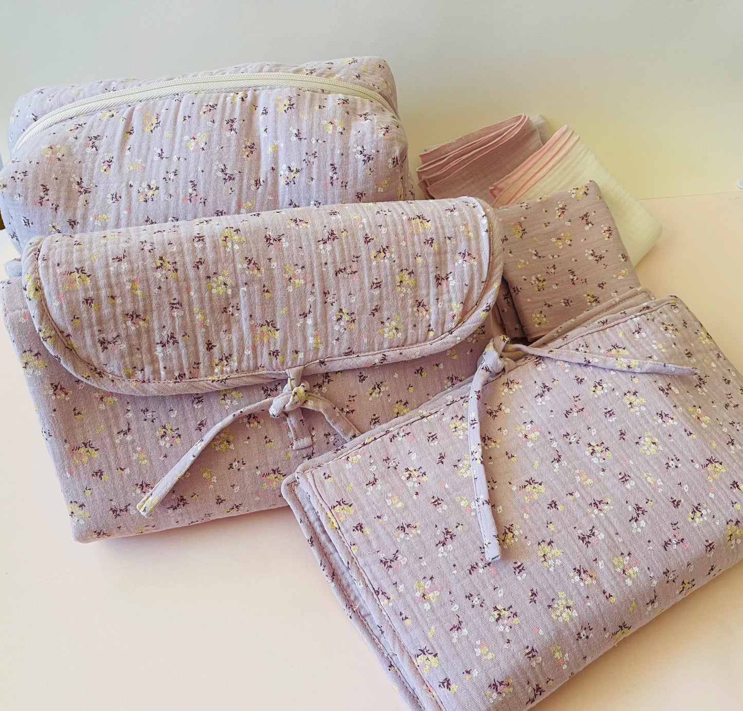 Conjunto de neceser, cambiador de paseo, y muselinas en tejido de muselina malva con flores amarillas y blancas