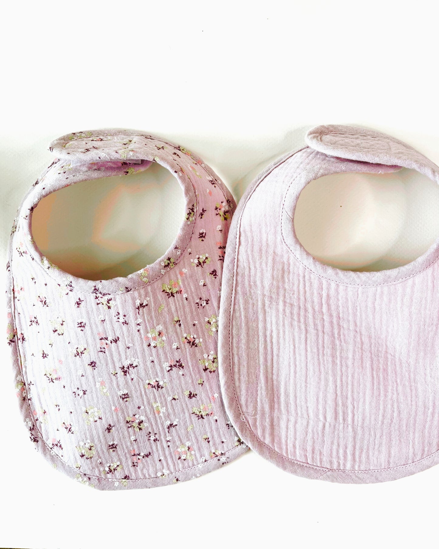 conjunto de dos baberos, el de muselina malva con florecitas amarillas y burdeos y el de color malva liso