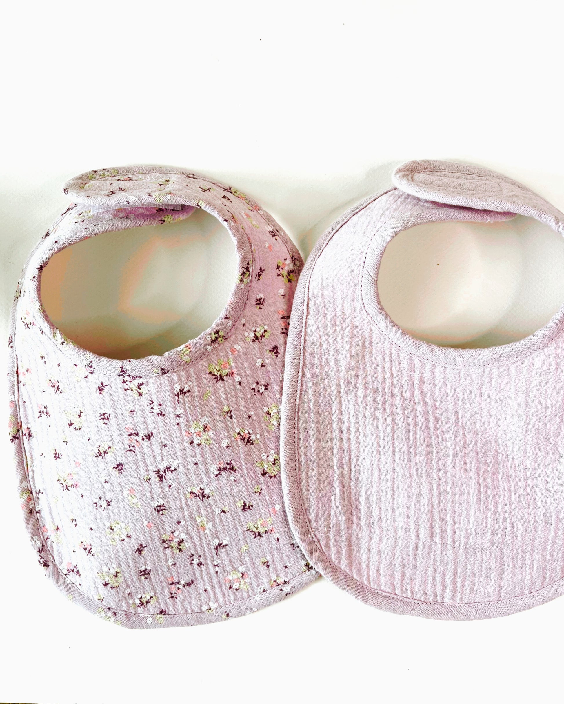 conjunto de dos baberos, el de muselina malva con florecitas amarillas y burdeos y el de color malva liso