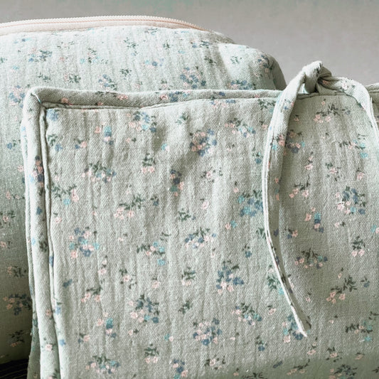 Conjunto de porta toallitas en muselina de color verde menta y flores azules y blancas con cierre en lazo; neceser del mismo tejido y cierre con cremallera